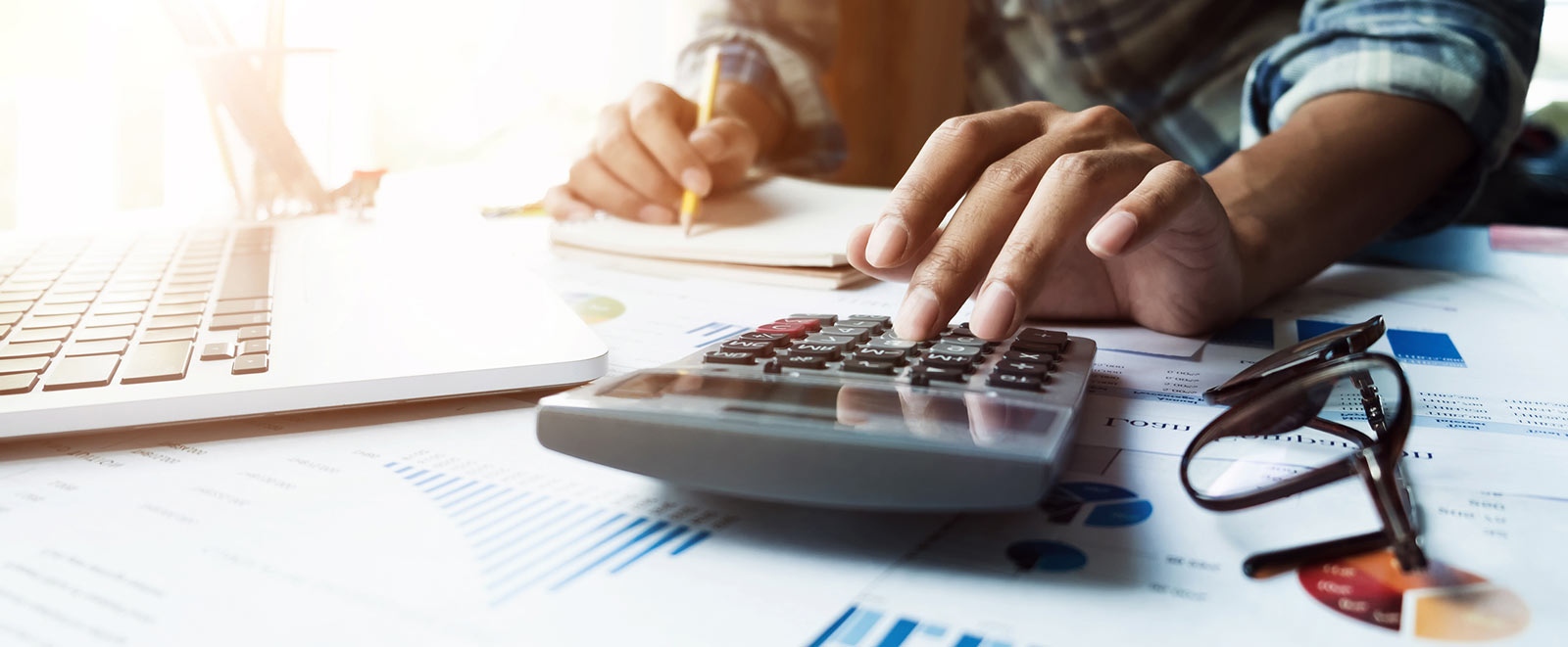 A man using a calculator and a laptop computer for finances