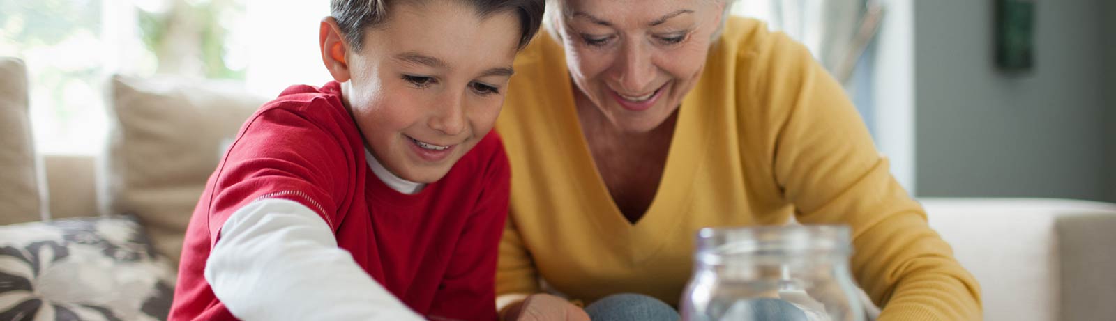 A grandmother and grandson saving coins in a jar